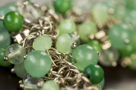 Close up view of pretty translucent green beads on an item of silver jewellery attached in a bunch...