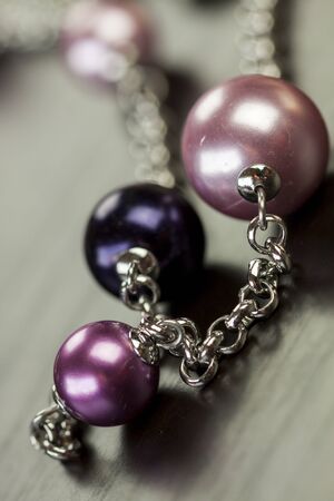 Close up of three attractive shiny purple beads attached by silver chains on an item of jewellery in a fashion and handicraft conceptの写真素材