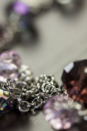 Close up of three attractive shiny purple beads attached by silver chains on an item of jewellery in a fashion and handicraft conceptの写真素材