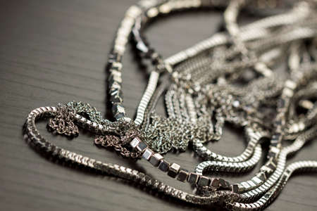 Pile of assorted silver chains with shiny box chains, cube chains and ordinary linked chain on a grey background conceptual of fashion jewelleryの写真素材