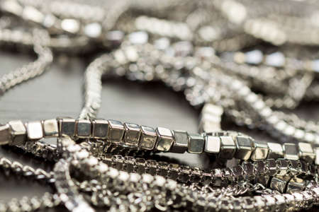 Pile of assorted silver chains with shiny box chains, cube chains and ordinary linked chain on a grey background conceptual of fashion jewelleryの写真素材