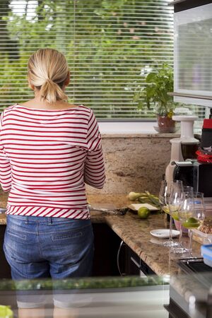 Attractive blond woman barbecuing meat outdoors in the garden grilling two marinated spicy beef steaks over a fireの写真素材