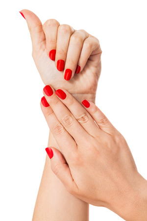 Woman with beautiful manicured red fingernails gracefully crossing her hands to display them to the viewer on a white background in a fashion, glamor and beauty conceptの写真素材