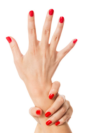 Woman with beautiful manicured red fingernails gracefully crossing her hands to display them to the viewer on a white background in a fashion, glamor and beauty conceptの写真素材