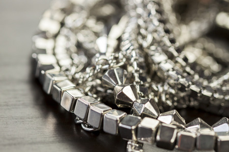 Pile of assorted silver chains with shiny box chains, cube chains and ordinary linked chain on a grey background conceptual of fashion jewelleryの写真素材