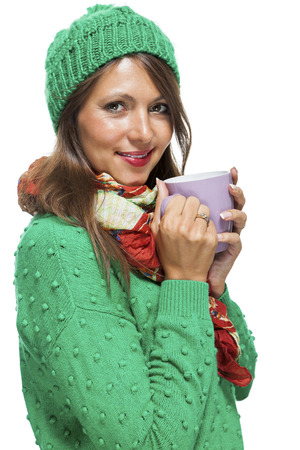 Close up Pretty Young Woman Wearing Green and Red Winter Fashion, Holding a Cup of Coffee While Smiling at the Camera. Isolated on White Background.の写真素材