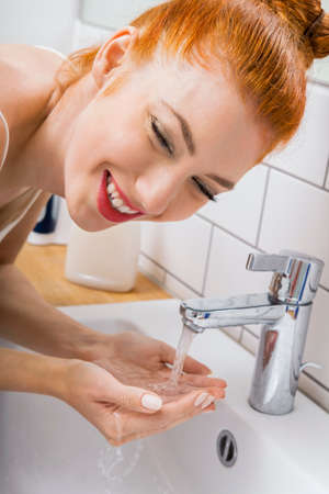 Close up Happy Young Woman Washing her Face While Looking at the Camera for a Moment.の写真素材