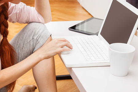 Pretty Young Woman Using her Laptop Computer In the Living Room with Feet on the Table and Showing Serious Face.の写真素材
