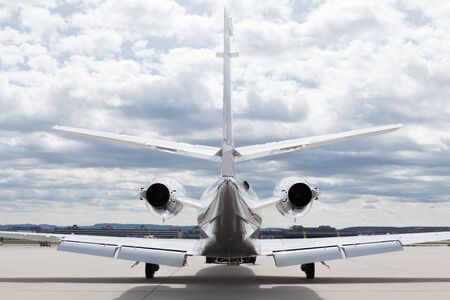 Aircraft learjet Plane in front of the Airport with cloudy sky and sunの写真素材