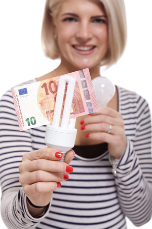 Woman holding an eco-friendly light bulb with a 10 Euro banknote threaded through it in a conceptual image of efficiency and savingsの写真素材