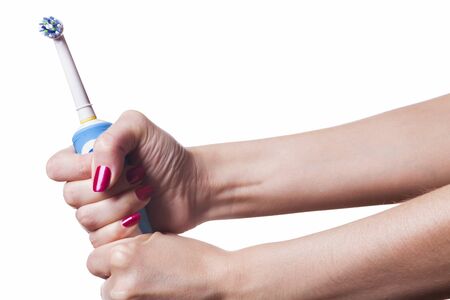 Hand with manicure holds single blue electric toothbrush against white backgroundの写真素材