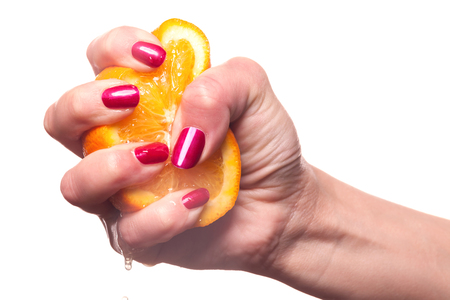 Hand with manicured nails painted a deep glossy red touch an orange on white backgroundの写真素材