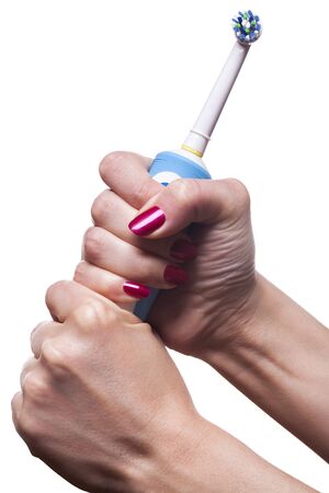 Hand with manicure holds single blue electric toothbrush against white backgroundの写真素材