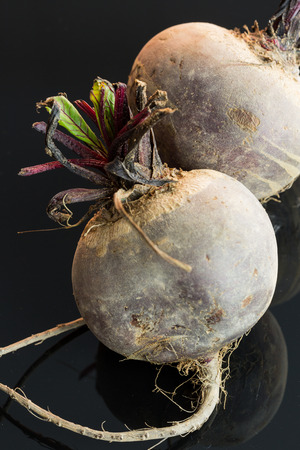 Three farm fresh whole raw beetroot in a close up view on a black surface in a healthy diet or vegetarian conceptの写真素材