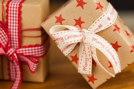 Close up vertical shot of several present boxes in kraft paper decorated with ribbons and red star...