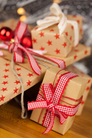 Close-up composition of Christmas present boxes of kraft paper with ribbons, decorations and stars patternの写真素材