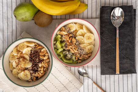 a top view of a table with two bowls with porridge and some fruit decoration.の写真素材