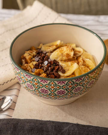 A close up view of a bowl with a porridge with banana, walnuts and chocolate chips.の写真素材