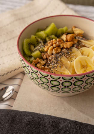 Close up view of a bowl of porridge with walnuts, kiwi and banana.の写真素材