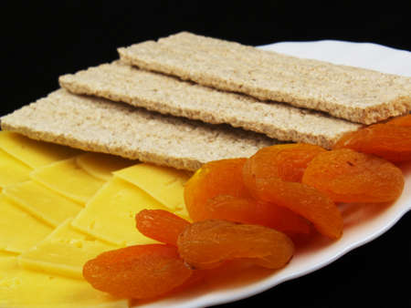 Dried fruits with cheese and diet wholegrain bread on the white plateの写真素材