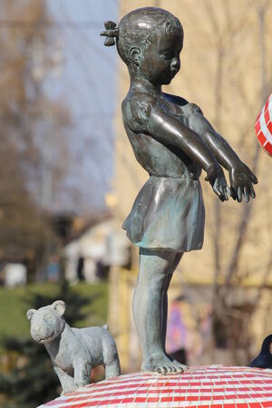 Old bronze statue of girl with dog in the parkの写真素材