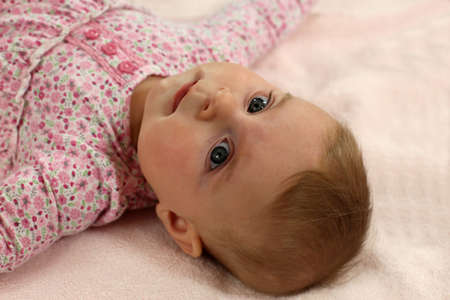 Little baby dressed in pink laying on the backの写真素材