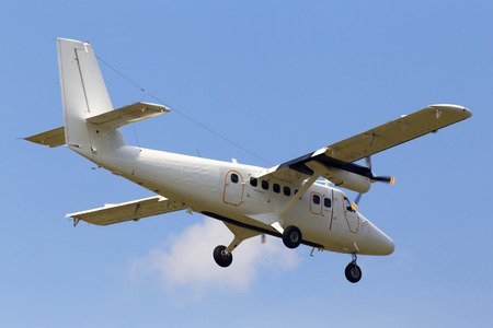 Small twin turboprop white aircraft on the cloudy sky background