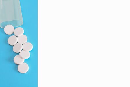 White pills spilled on a blue pastel background. Drugs and pills. Opioid epidemic.の写真素材