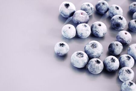 Frozen blueberry berries close-up on a lilac background. Berries in snow. Copy space.