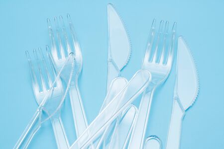 Plastic disposable tableware, cutlery. Fast food. Clean plastic forks and knives on blue background....