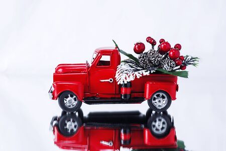 Christmas bouquet with berries in a red Christmas truck on a white background, reflected in a mirror surface. Concept - greeting card for Christmas and New Year, holiday delivery. Copy spaceの写真素材