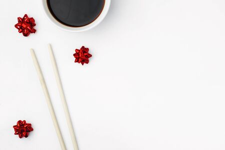 Bamboo sushi sticks are isolated on a white background, next to soy sauce and red bows. Concept festive background, greeting card, menu for oriental restaurant. Copy spaceの写真素材