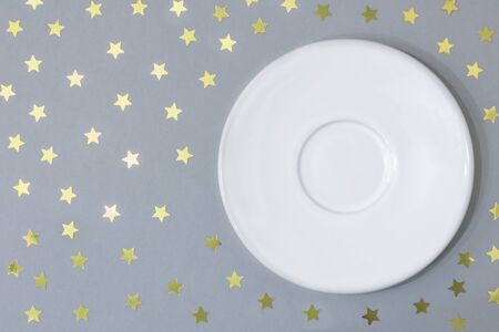 Empty plate saucer on a gray background with stars. Concept Christmas and New Year, holiday. Copy spaceの写真素材