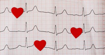 Red hearts on a cardiogram, a heartbeat symbol. Close up of an electrocardiogram in paper form. Healthcare and medical concept. Copy spaceの写真素材