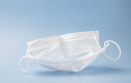 Typical 3-ply surgical mask to cover the mouth and nose. Surgical mask with rubber ear straps. Concept of medicine and healthcare, anti-virus procedures. Selective focus. Copy spaceの写真素材