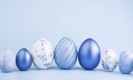 Chicken eggs painted in blue on a blue background. Creative card with Easter. Copy space
