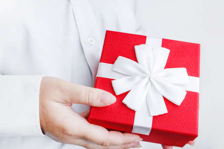 Red box with a bow in female hands.の写真素材