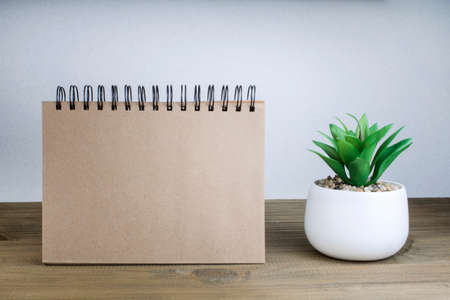 An open notebook with blank pages next to a green plant in a pot on a wooden table. Copy space. Retro style.の写真素材