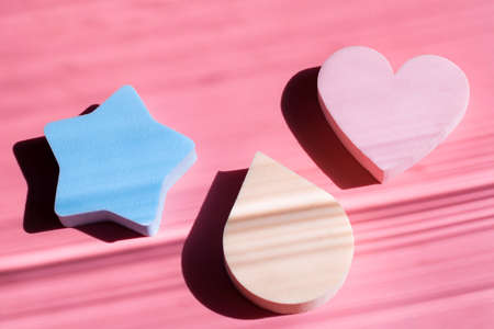 Cosmetic sponges in pastel colors on a pink background with deep shadows. Beauty concept. Copy spaceの写真素材
