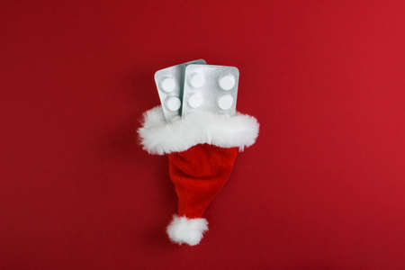 Medical Christmas background. Pills, blister in santa claus hat, on a red background. Banner....