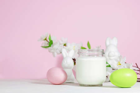 Organic probiotic milk kefir drink or yogurt in a glass container, with colored Easter eggs, on a...