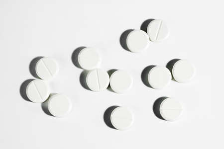 White pills isolated on a white background with hard shadows. Medicine and drugs concept. View from...