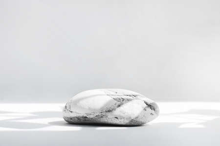Background for cosmetics in natural white-gray color. Stone podium on a white background with hard shadows.の写真素材