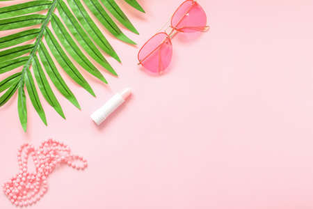 Women's fashion accessories and cosmetics of pink color isolated on pink background with palm leaf. Pink glasses. Magazines, social networks. View from above. Flat lay.の写真素材
