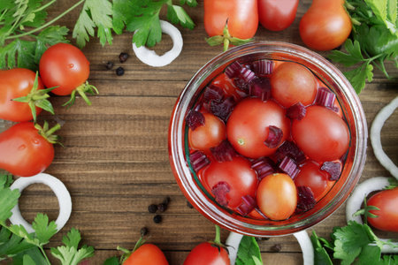 The process of harvesting, canning, salting or pickling red tomatoes. Tomatoes in a glass jar with pickle, onions, peppers and herbs on an old rustic background. Fermented foods. Flat lay. Top View.