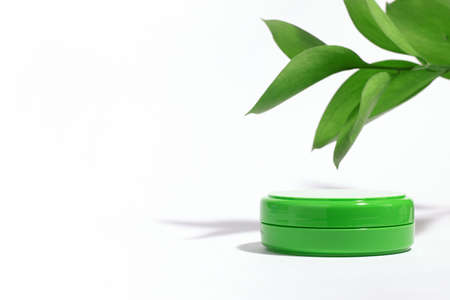 The background is cosmetic. Green empty container with face cream moisturizer isolated on white...