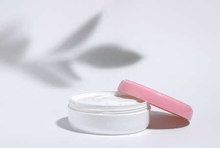 The background is cosmetic. White jar of moisturizing face cream with pink cap isolated on white...