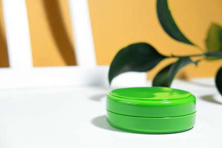 The background is cosmetic. Moquet green empty container with moisturizing or protective face cream...