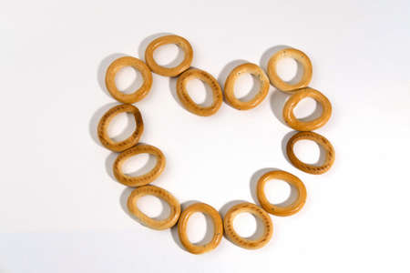 Traditional Russian folk dishes for tea, round or oval drying, isolated on white background in the shape of a heart. Dried baked bagels. Dessert.の写真素材