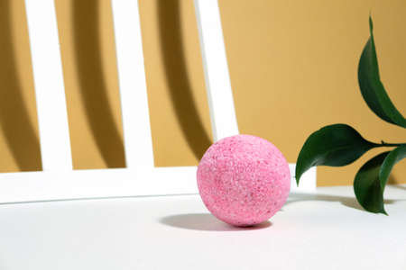 Pink salt bomb on a creative orange beige white background, with geometric lines, plant and hard shadows. Mineral cosmetics creative layout. Spa care. Copy spaceの写真素材